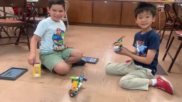 Two campers testing LEGO robots with tablets