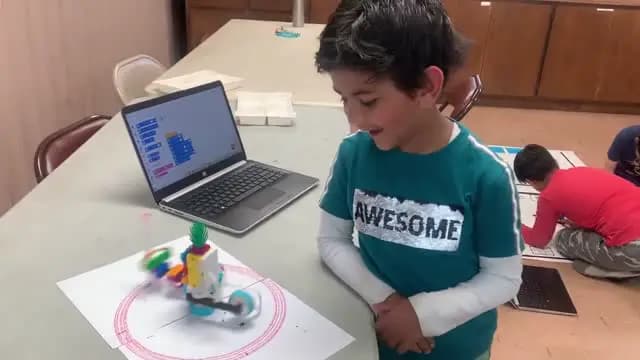 Camper smiling beside the robot he coded at STEM4Kids Cupertino summer camp